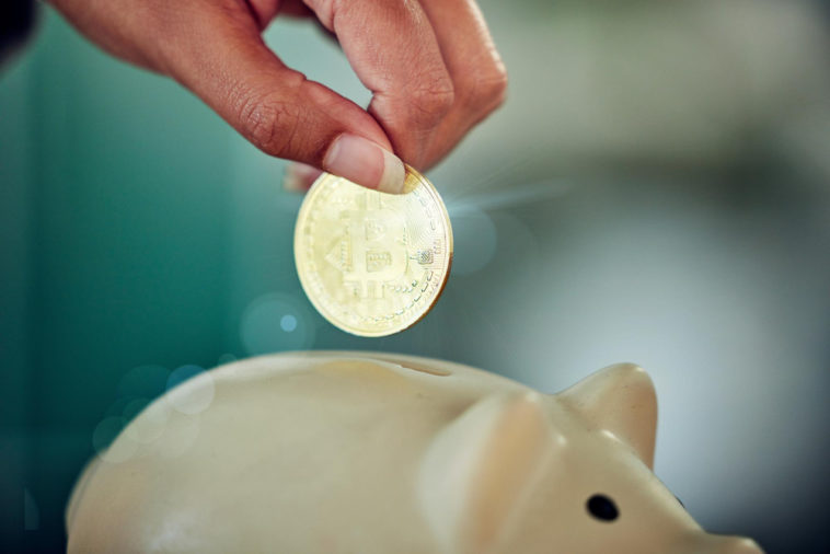 hand putting bitcoin into a piggy bank