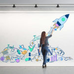 woman drawing startup concepts on a large white canvas