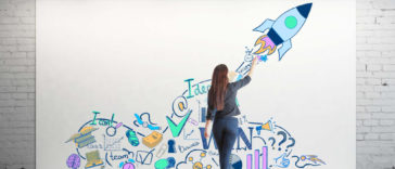 woman drawing startup concepts on a large white canvas