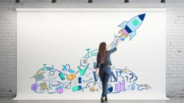 woman drawing startup concepts on a large white canvas