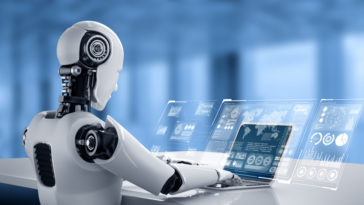 robot sitting at a table and typing on a laptop