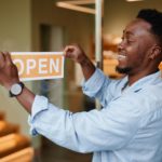 joyful young african-american man opening a cafe