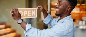 joyful young african-american man opening a cafe