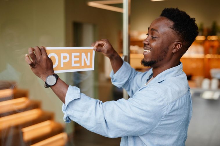 joyful young african-american man opening a cafe